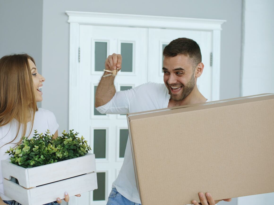 A couple with keys and moving boxes in their new home.