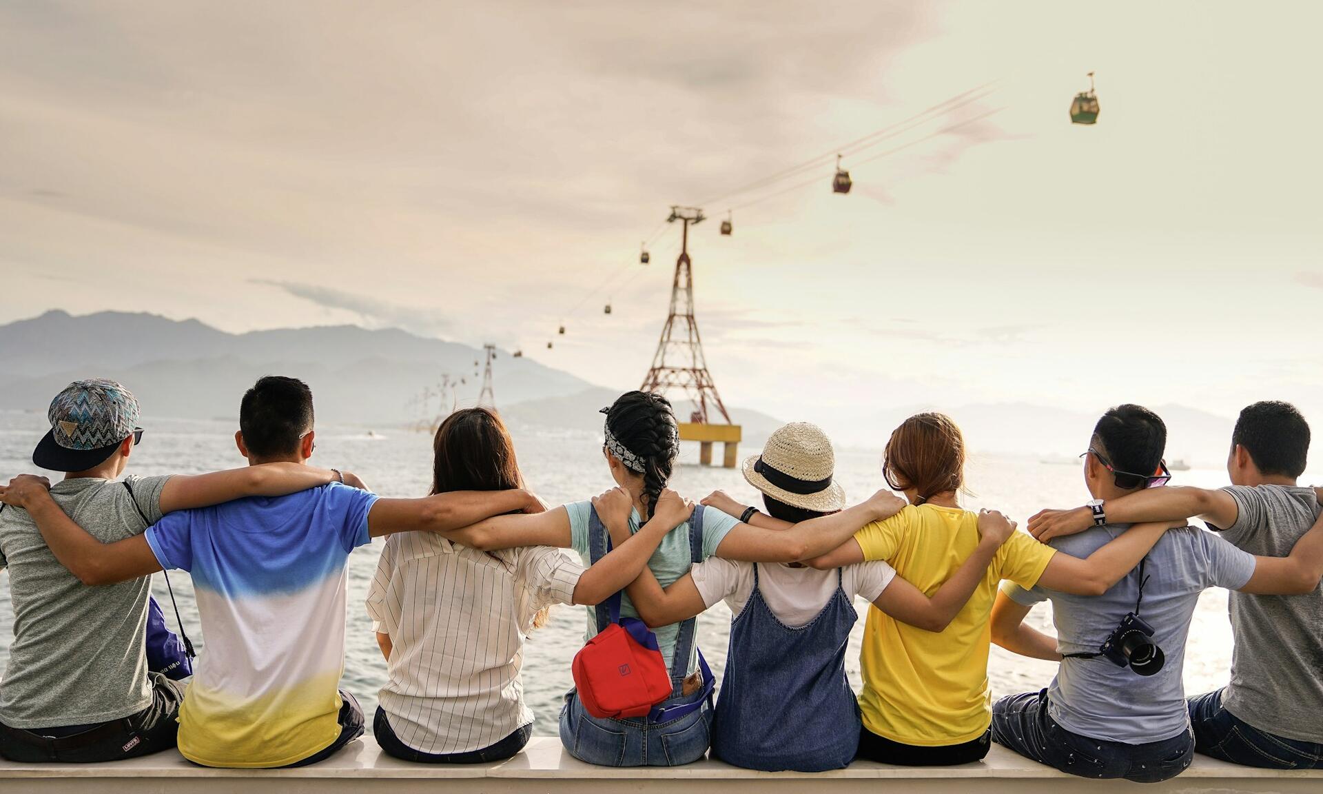 Friends and family together, arms around one another, looking out over the water.
