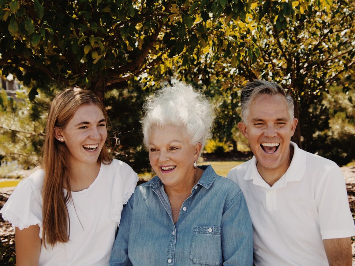Three generations of a family laughing together outdoors.